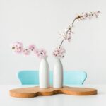 Japanese Design - two pink petaled flowers in white vases on brown wooden surface