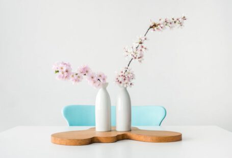 Japanese Design - two pink petaled flowers in white vases on brown wooden surface