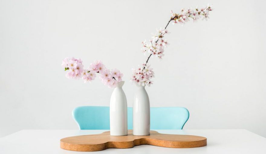 Japanese Design - two pink petaled flowers in white vases on brown wooden surface