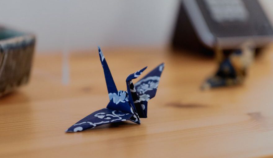 Japanese Crafts - a blue origami bird sitting on top of a wooden table