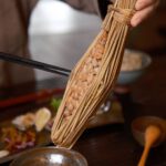 Japanese Breakfast - a person holding a stick over a bowl of food